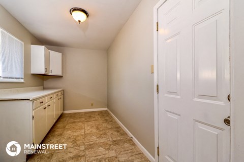 a small kitchen with white cabinets and a white door