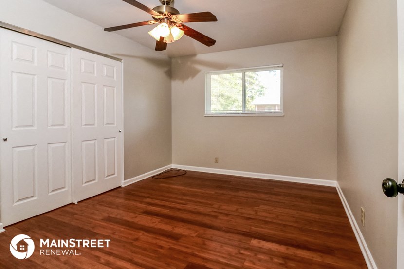 the master bedroom has a hardwood floor and a ceiling fan