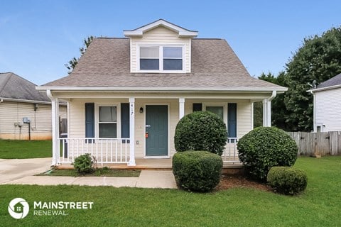 a small white house with a porch and a lawn