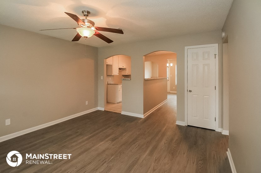 the living room and kitchen of an open floor plan with a ceiling fan