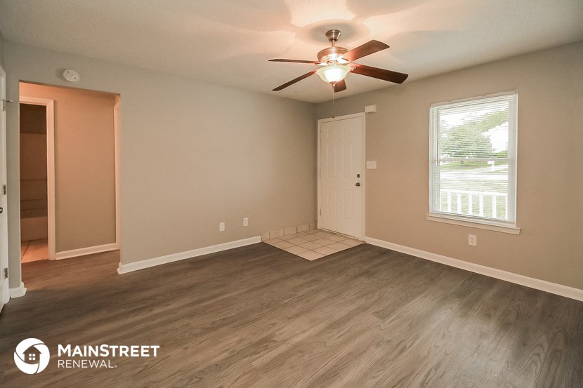 the living room of an empty house with a ceiling fan