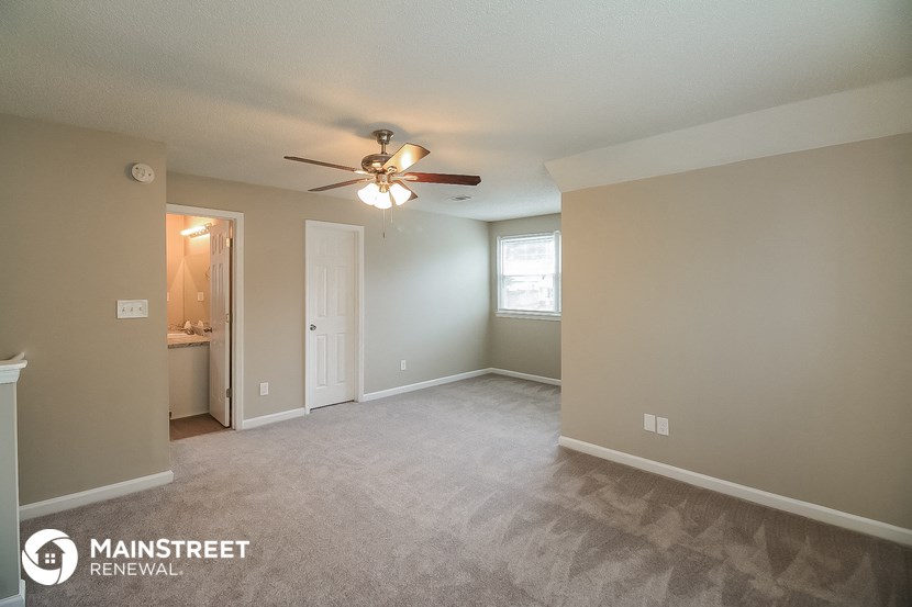 the spacious living room with carpet and ceiling fan