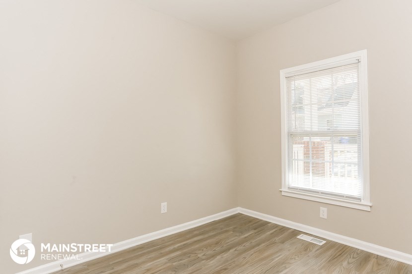 the bedroom of an apartment with wood flooring and a window