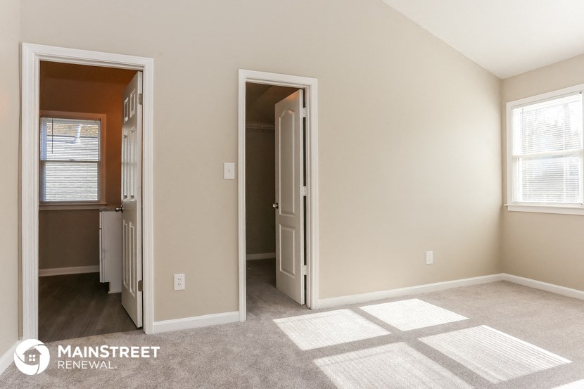 a living room with a carpeted floor and a door to a closet and a