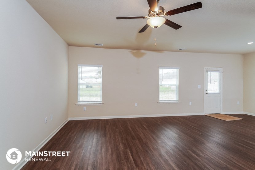 an empty living room with wood flooring and a ceiling fan
