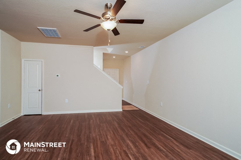 an empty living room with a ceiling fan and white walls