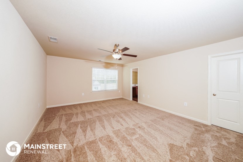 a spacious living room with carpet and a ceiling fan