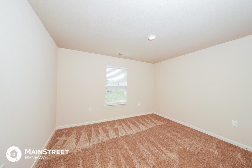 the spacious living room with carpeting and a window
