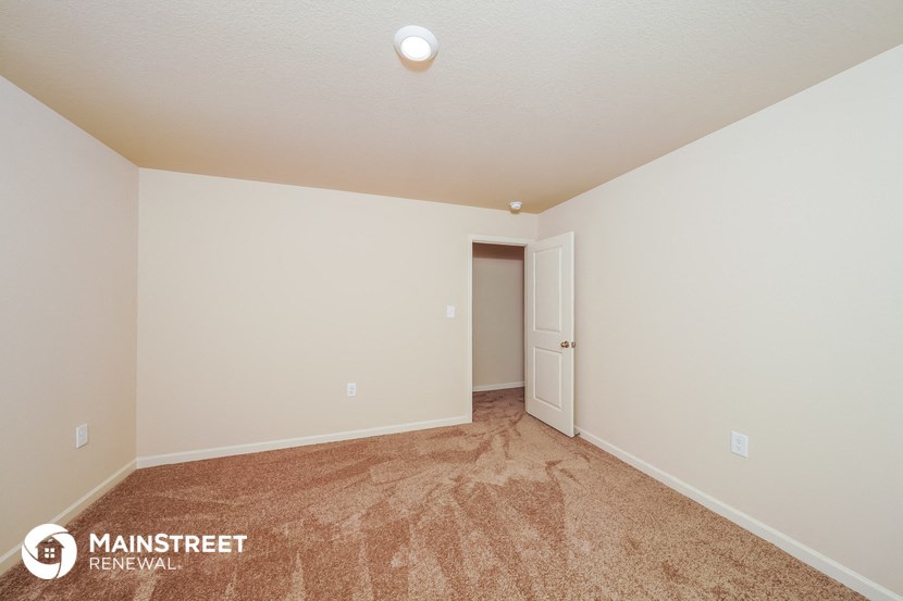 a spacious living room with carpet and a door to a closet