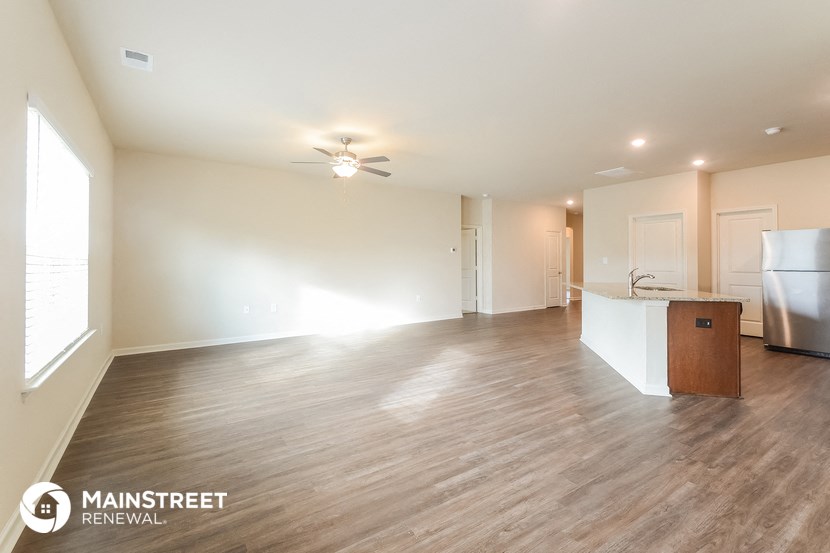 the living room and kitchen of an apartment with wood flooring