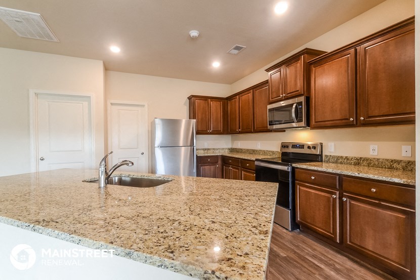 a kitchen with granite countertops and wooden cabinets and stainless steel appliances