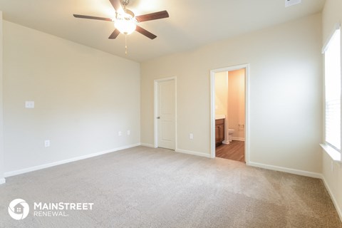 a spacious living room with carpet and a ceiling fan