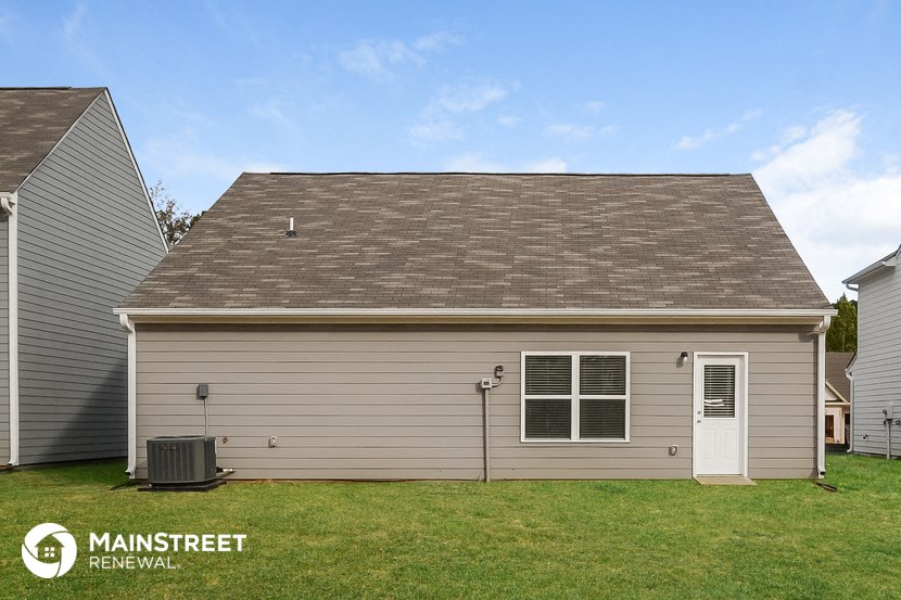the front of a gray house with a yard and a white door