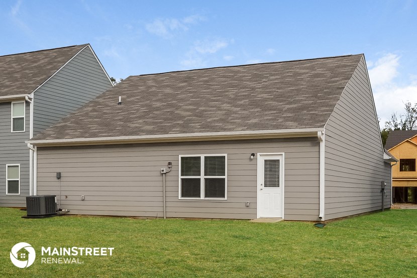 the front of a gray house with a white door and a green lawn