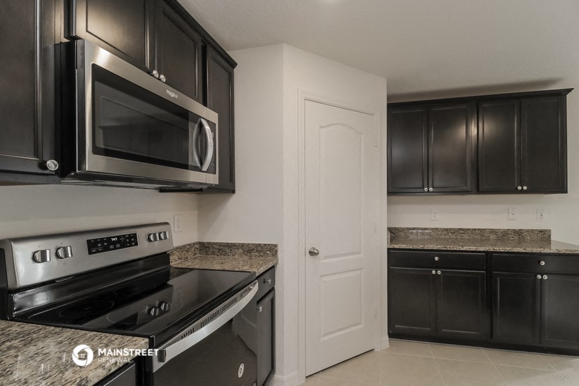 a kitchen with black cabinets and stainless steel appliances