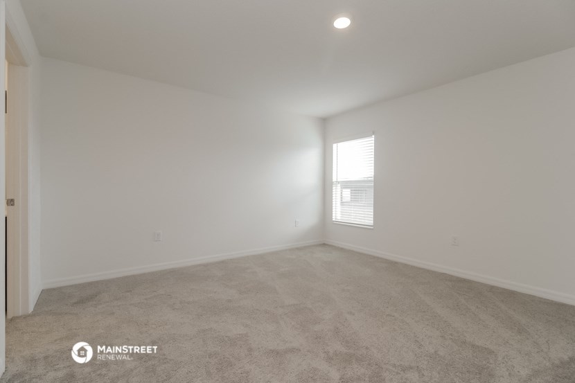 a bedroom with white walls and carpet and a window