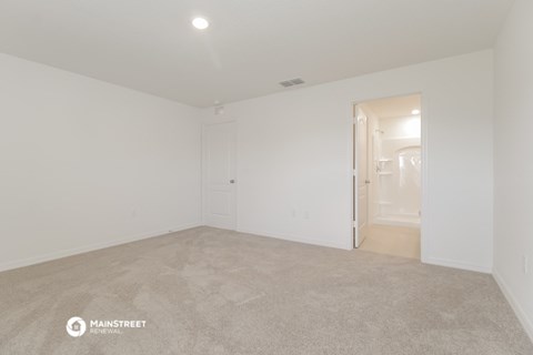 the living room of an apartment with white walls and carpet