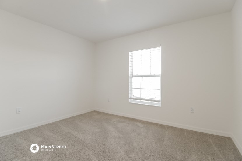 a bedroom with white walls and a window