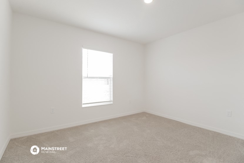 a bedroom with white walls and a window