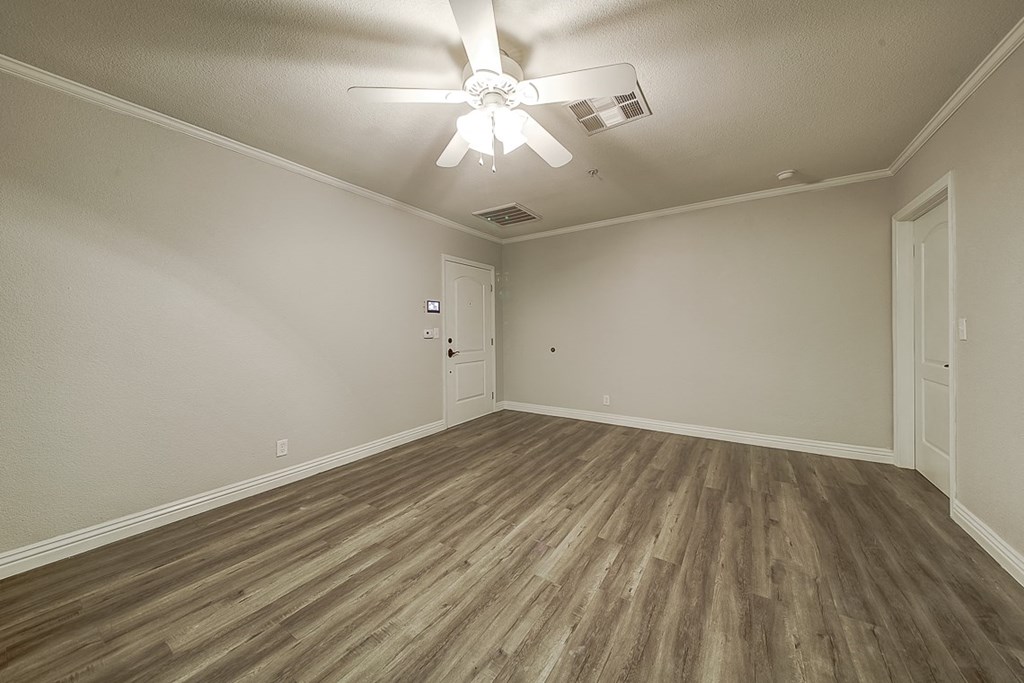 an empty living room with wood flooring and a ceiling fan