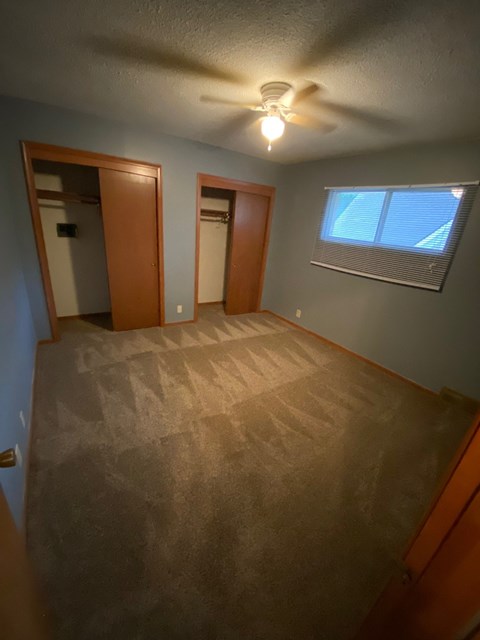 a empty room with a ceiling fan and a window