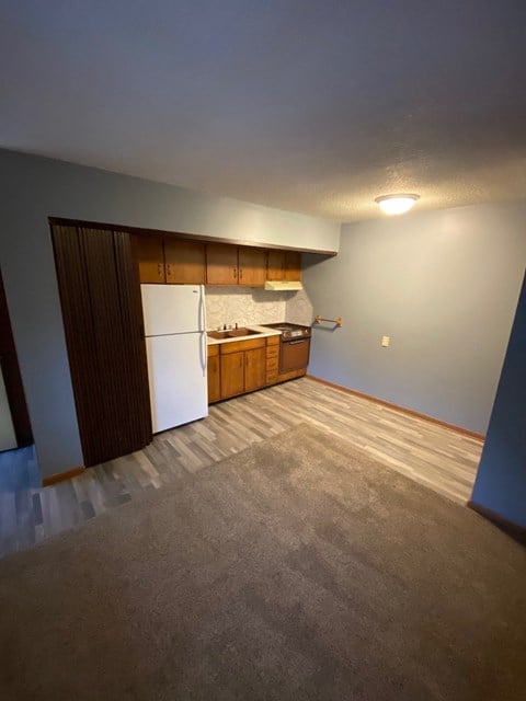 a empty kitchen with a refrigerator and wooden cabinets