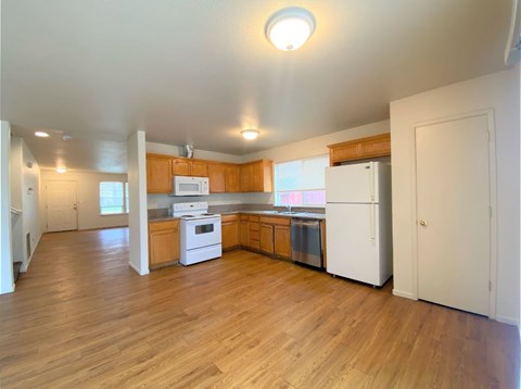 an empty kitchen with wood floors and white appliances