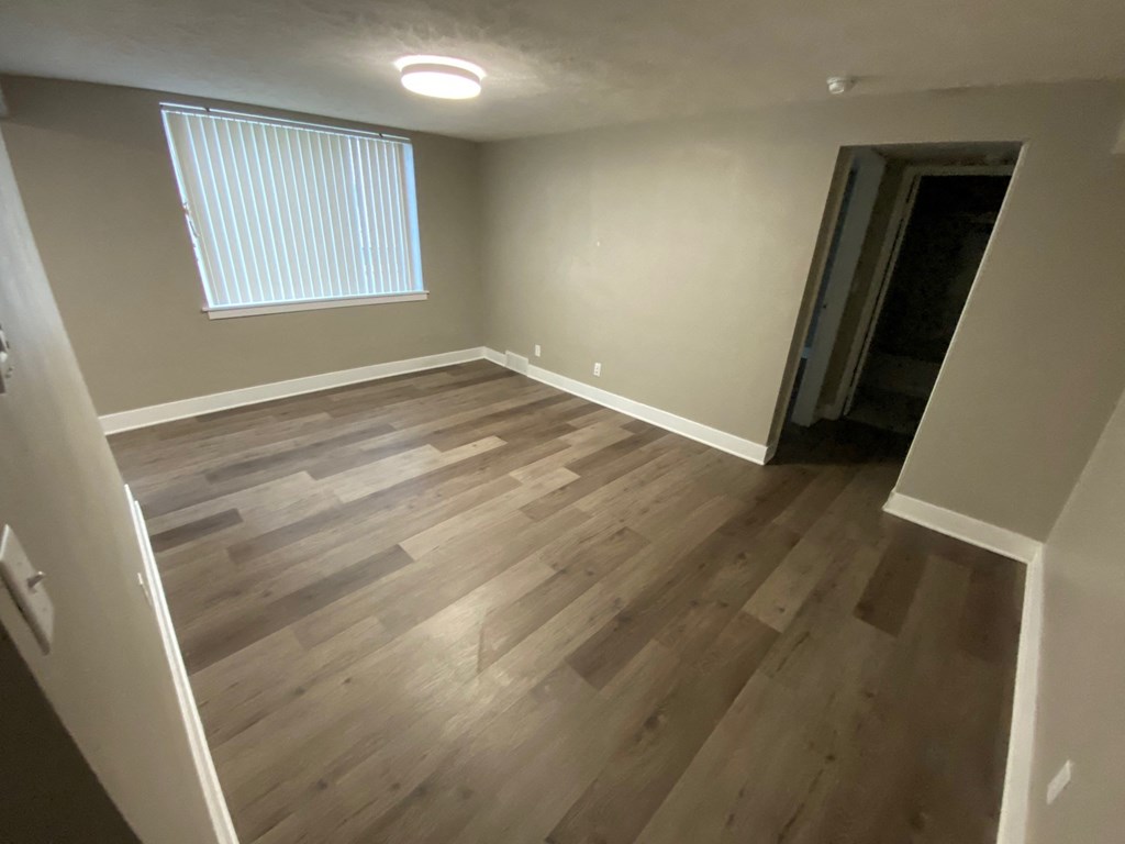 a empty living room with wooden floors and a window