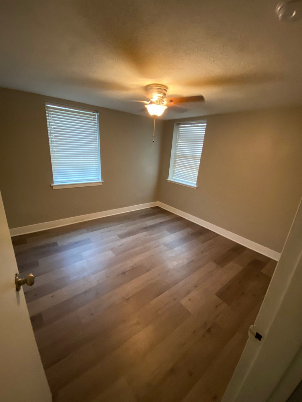 an empty room with wooden floors and a ceiling fan