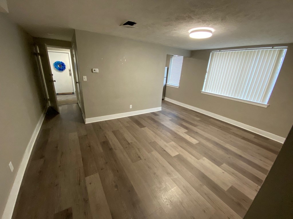 a living room with hardwood floors and a door into a hallway