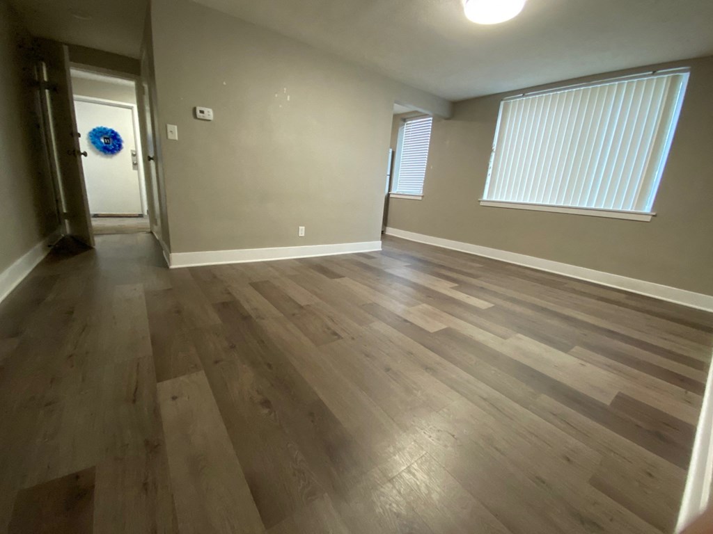 an empty living room with wooden floors and a door