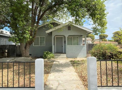 A house with a grey front yard and a black fence.