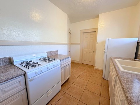 A kitchen with a white stove and a white refrigerator.
