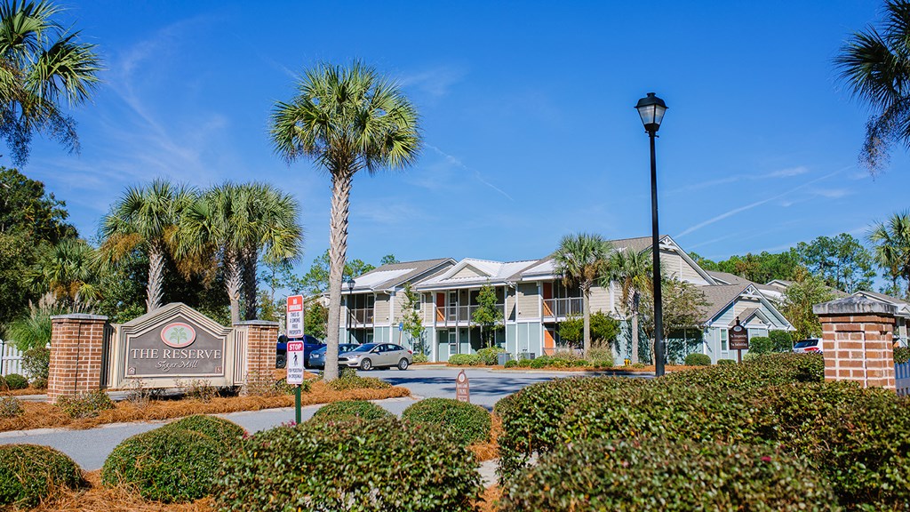 an apartment building with palm trees and a street sign