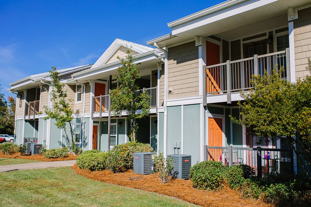 an exterior view of an apartment building with trees and a sidewalk