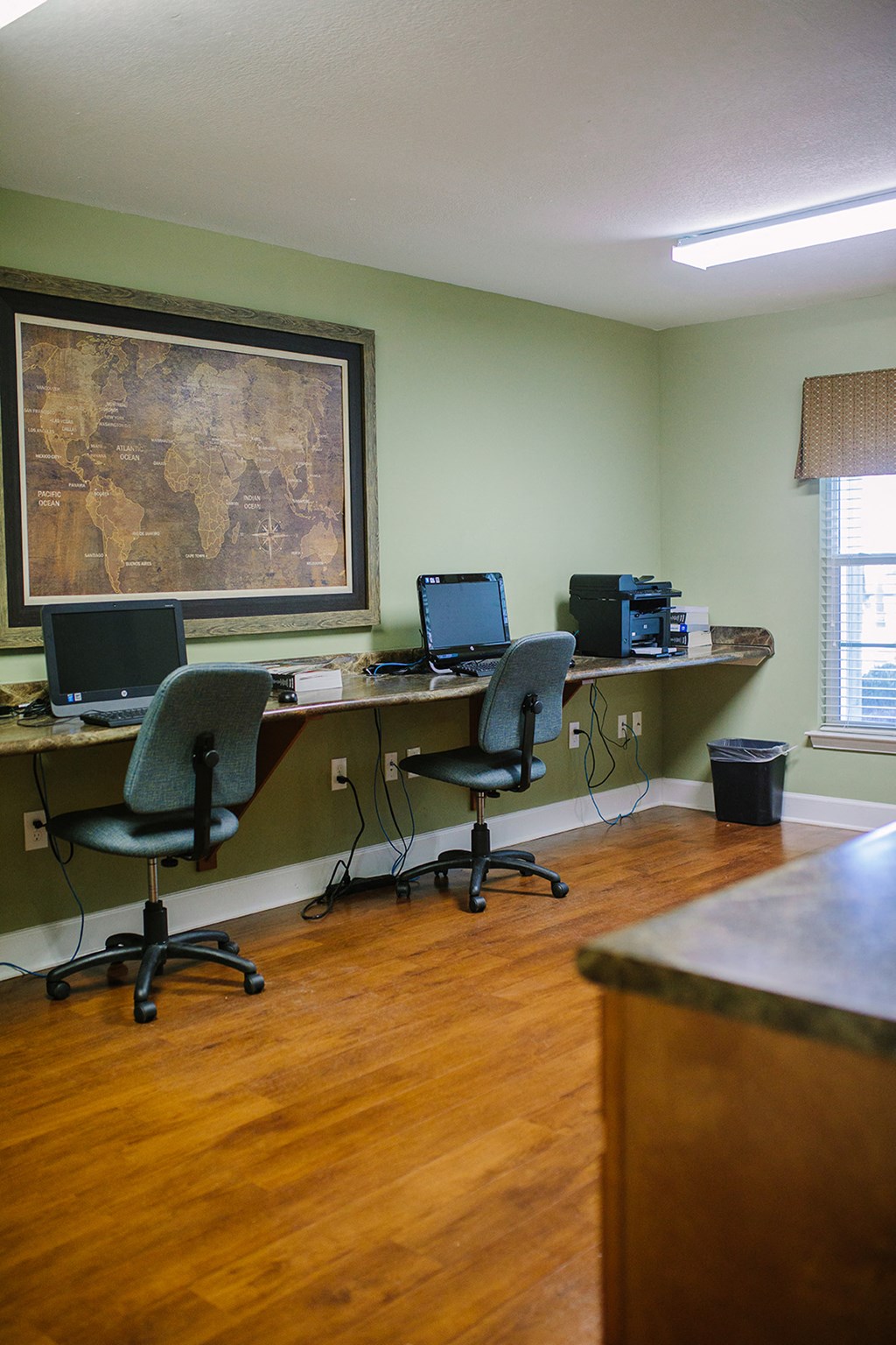 an office with a desk with two computers and a bulletin board