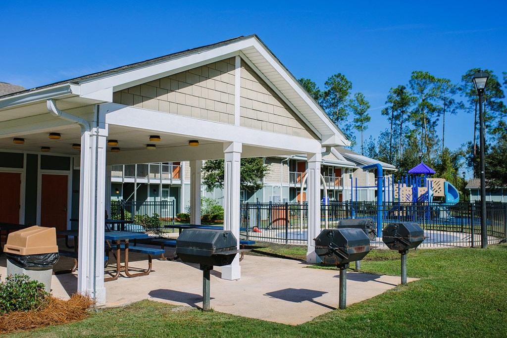 a clubhouse with a patio and grill in front of a house