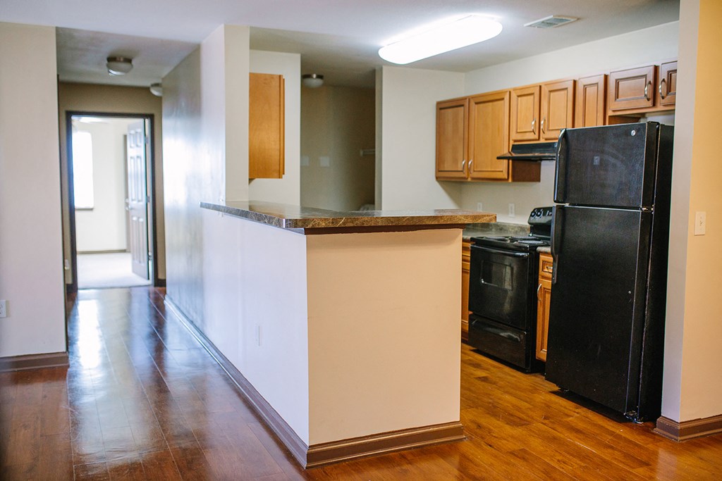 an empty kitchen with a counter and a black refrigerator