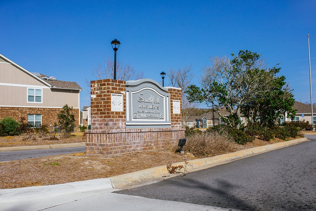 a sign on the side of a street in front of some houses
