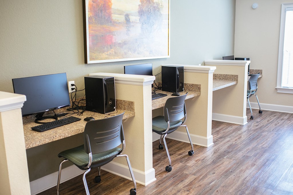 an office with desks and computers and a painting on the wall