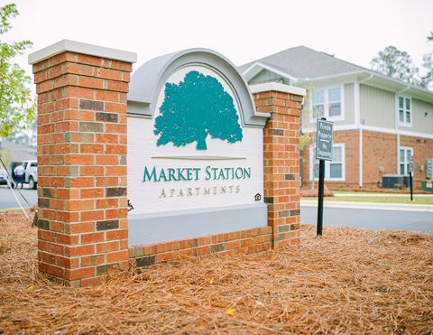 a sign for market station apartments in front of a brick building