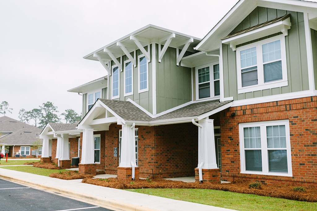 a row of homes with white columns and green roofs