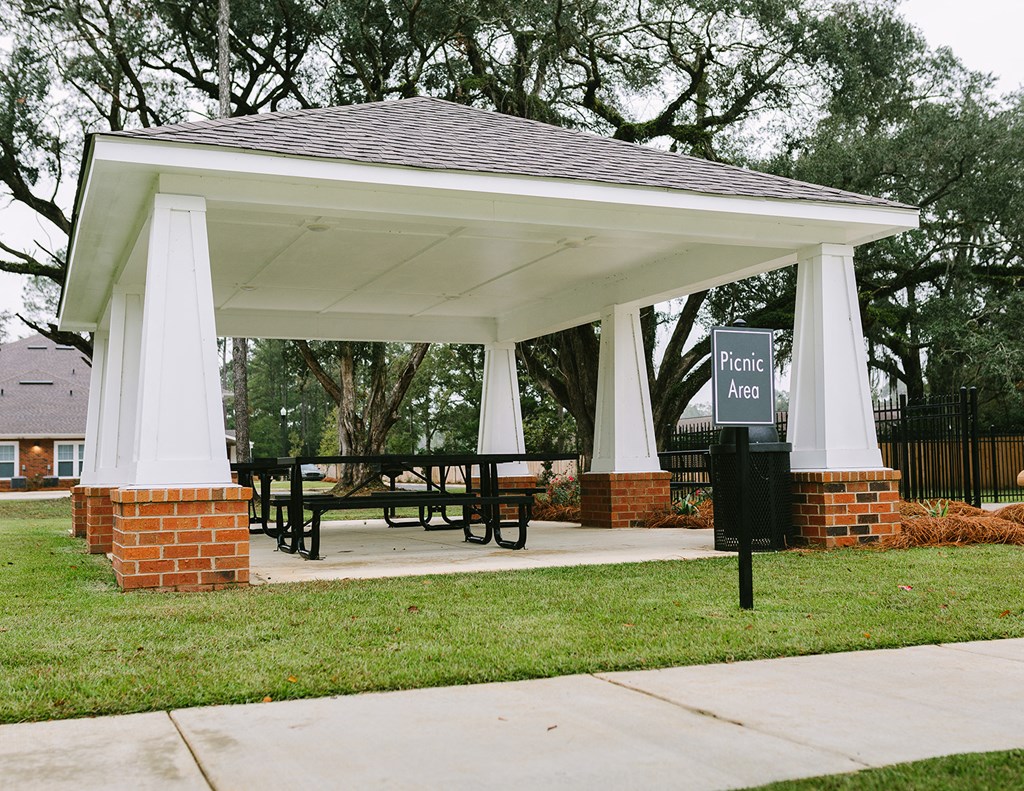 a gazebo with a picnic table and a sign on the grass