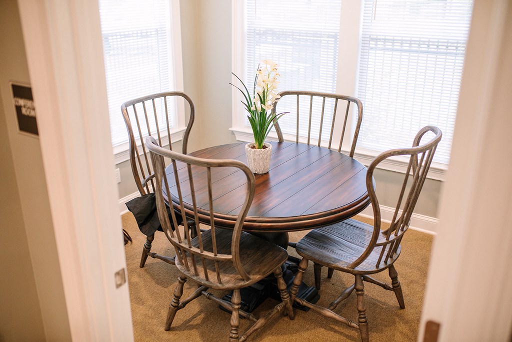 a dining room table with chairs and a vase with flowers on it