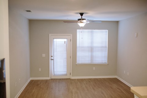 an empty living room with a ceiling fan and a window
