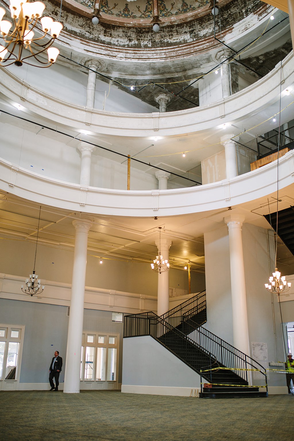 a man standing in the lobby of a large building with a spiral staircase