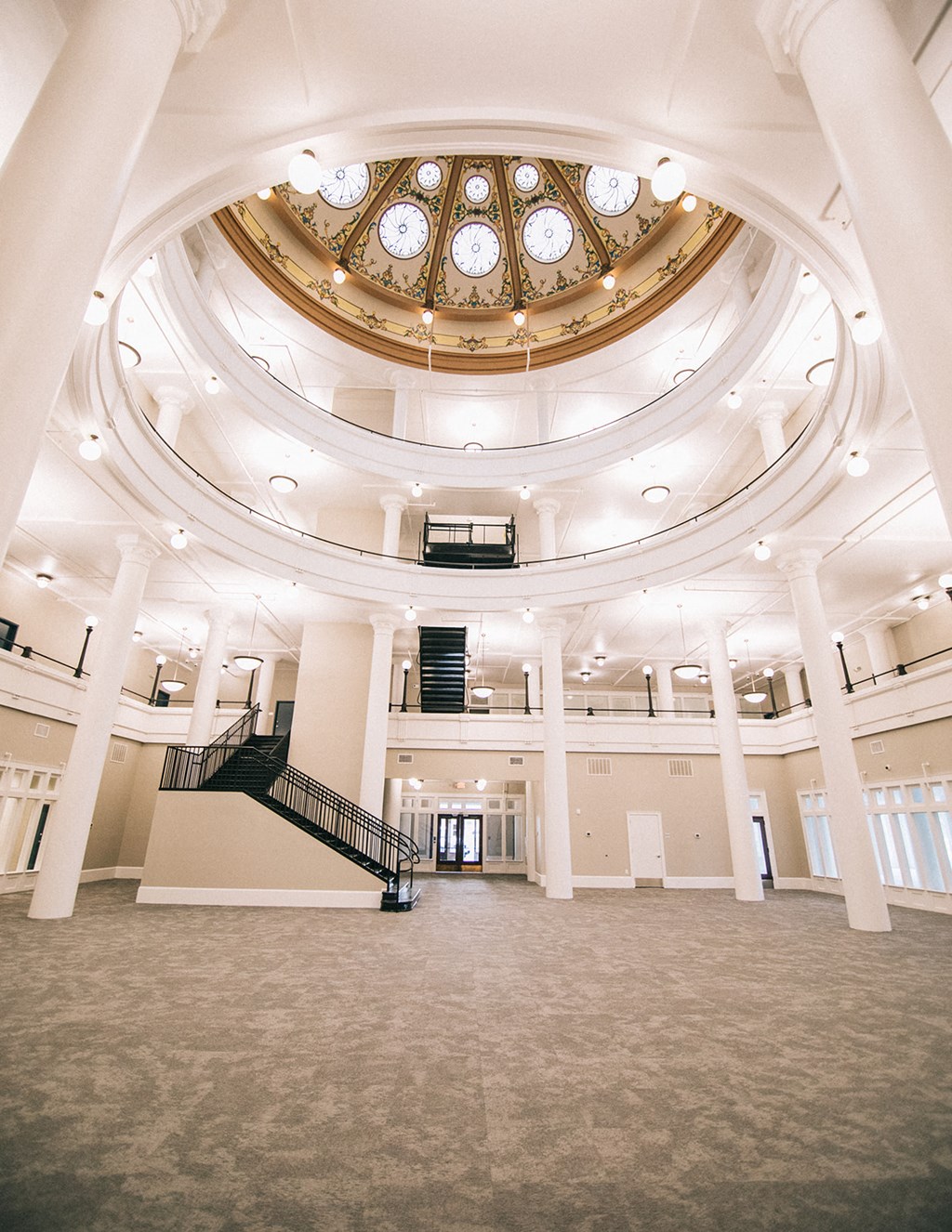 the inside of a large room with a staircase and a ceiling with many windows