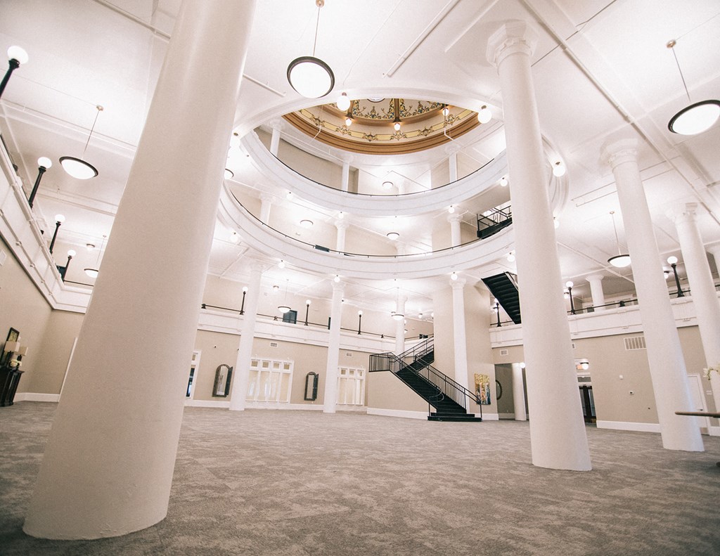 a large room with pillars and a staircase in the middle of it