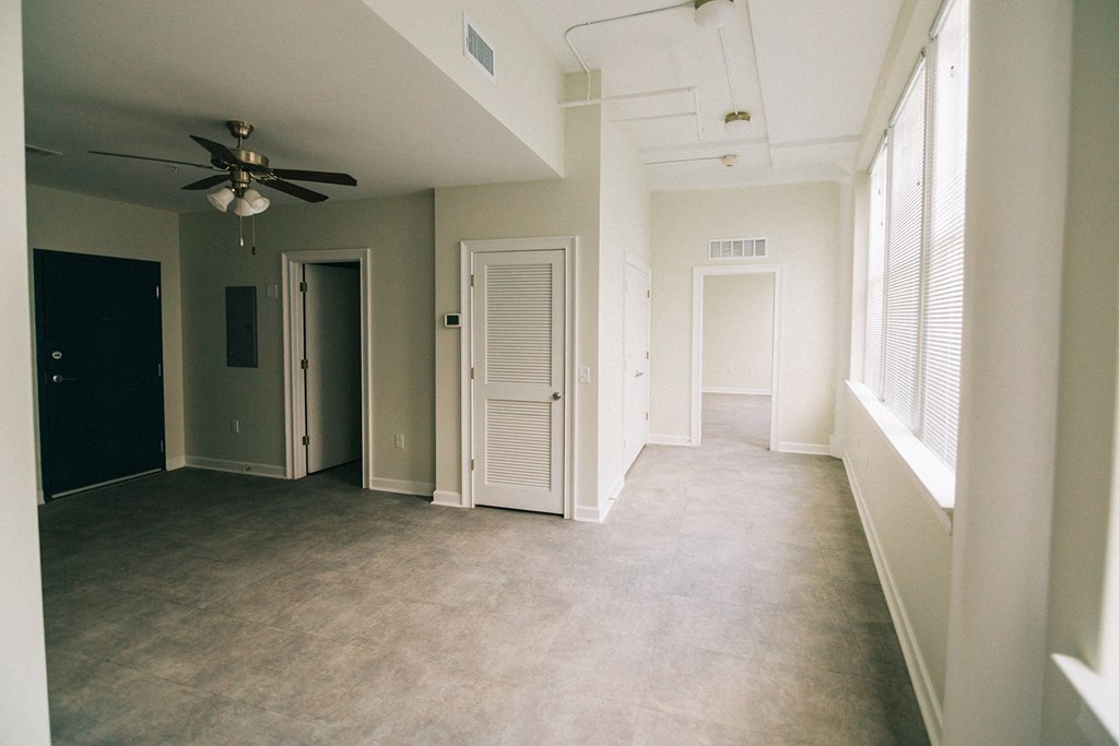 an empty living room with a ceiling fan and windows