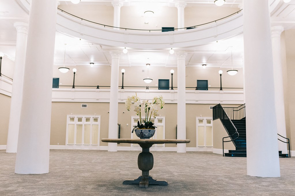 a large room with pillars and a table with flowers in it